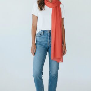 Femme portant une écharpe longue porté autour du cou en 100% laine douce et légère coloris corail